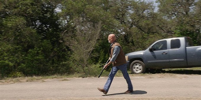 Walker Bonham walking with a shotgun ready to fire.