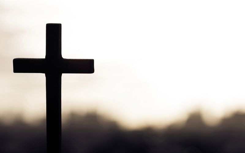 black and white image of a cross against a gray landscape background