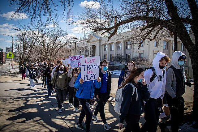 A long line of high school students, double and sometimes triple file, march past a squat, neo-classical government building on their way to the Des Moines, Iowa governor's mansion on Terrance Hill to protest attacks on trans students wishing to play sports. A long line of high school students, double and sometimes triple file, march past a squat, neo-classical government building on their way to the Des Moines, Iowa governor's mansion on Terrance Hill to protest attacks on trans students wishing to play sports.