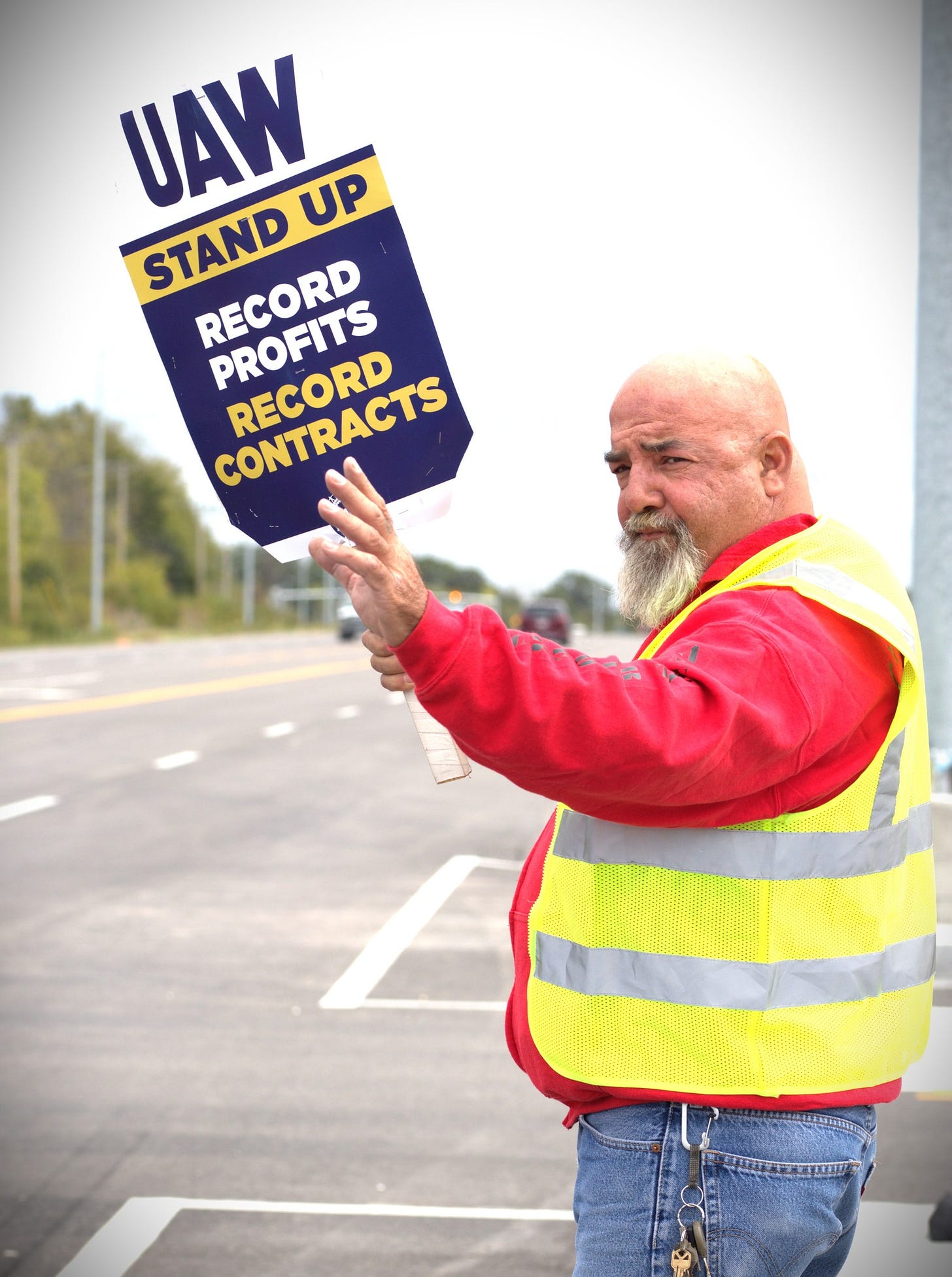May be an image of 1 person, road and text that says 'STAND UAW UP RECORD PROFITS CONTRACTS RECORD'