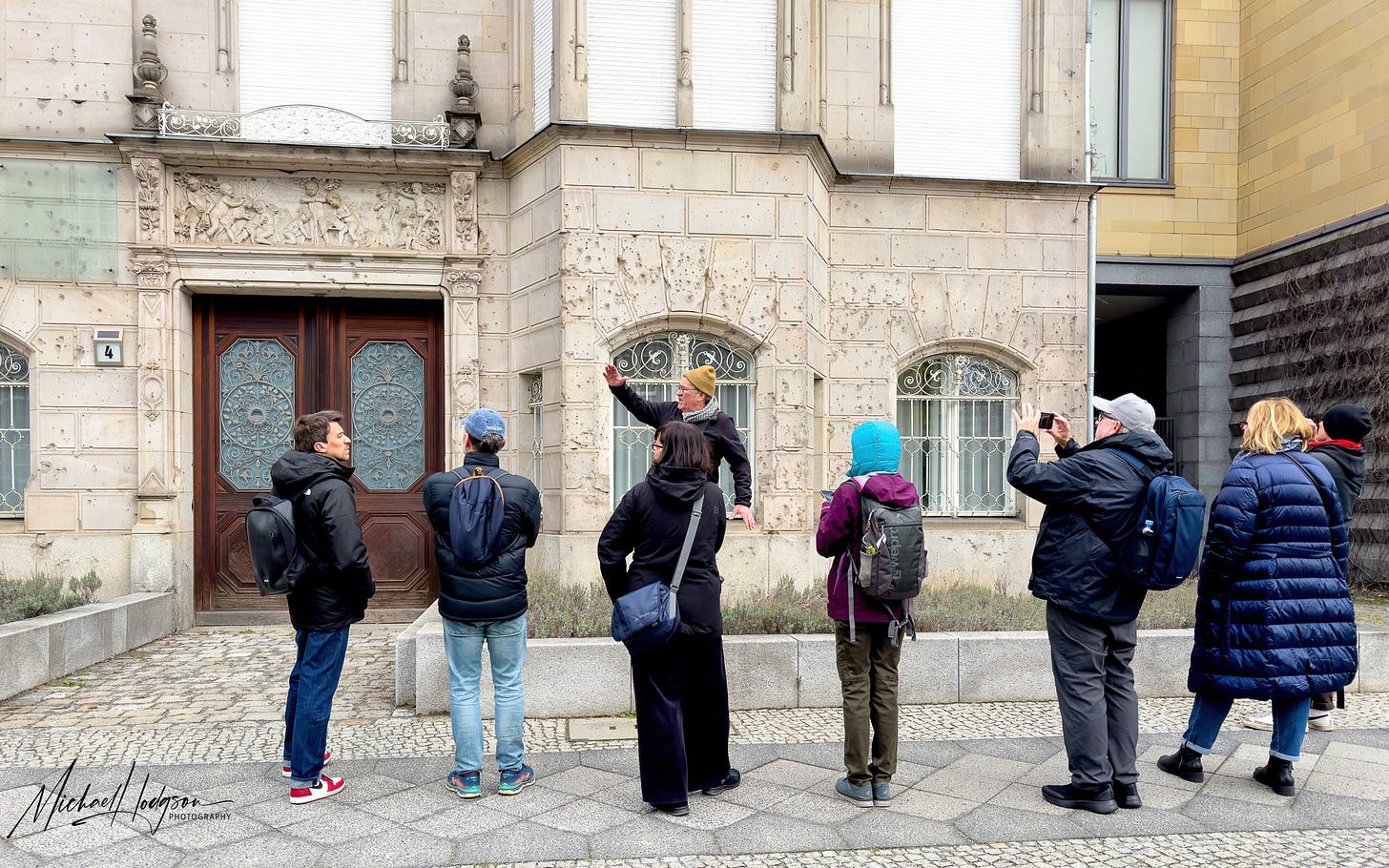 Peter Graham pointing out machine gun bullet marks on a building in the Berlin Battle Damage tour. 