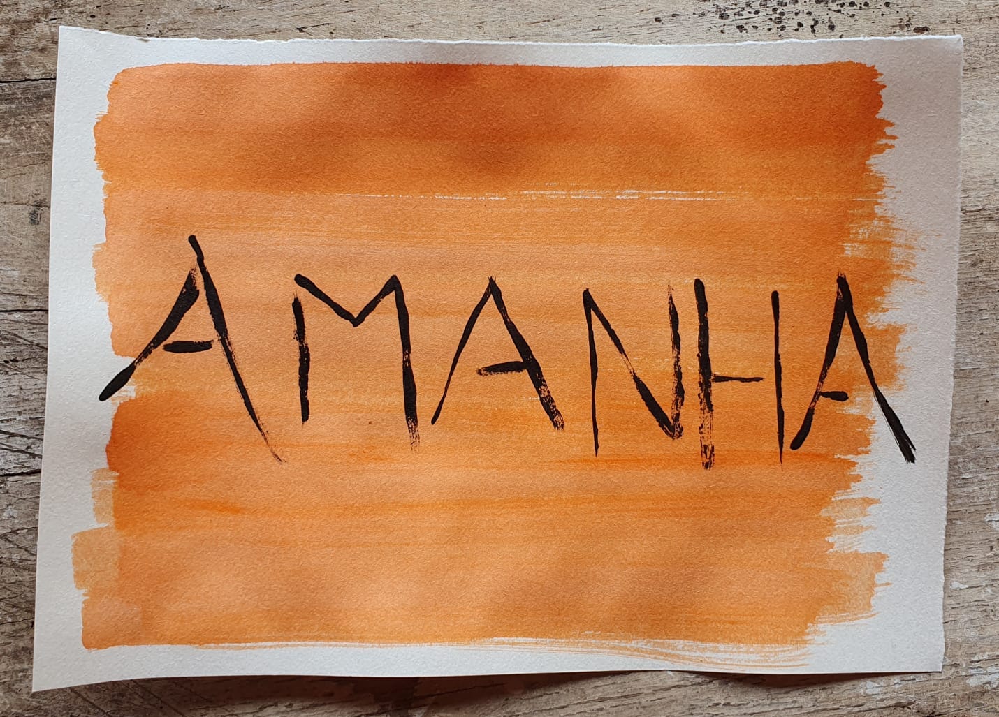 Fotografiaa de um papel com um fundo pintado de laranja e a palavra AMANHA escrita em preto. O papel está em um fundo de mandeira.