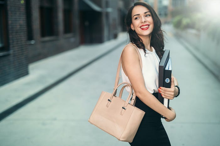 A woman holding work binders walking on the street.