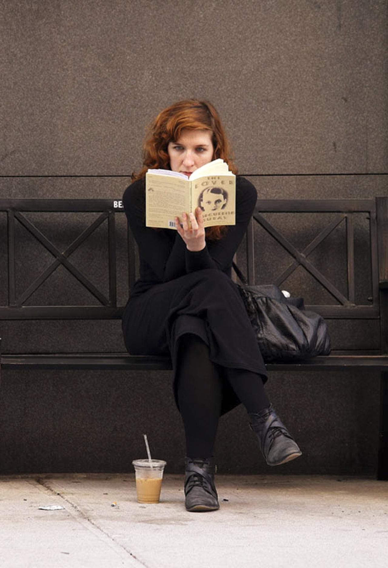 A woman reads "The Lover" by Marguerite Duras on East 12th Street.