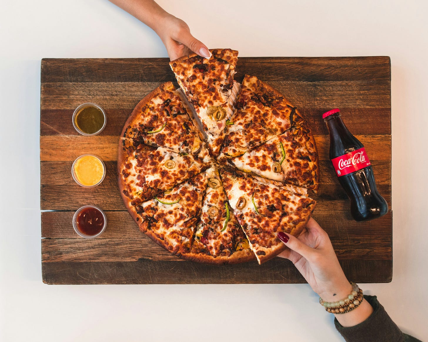 Deep-dish pizza on a wood board with a coca-cola bottle next to it.