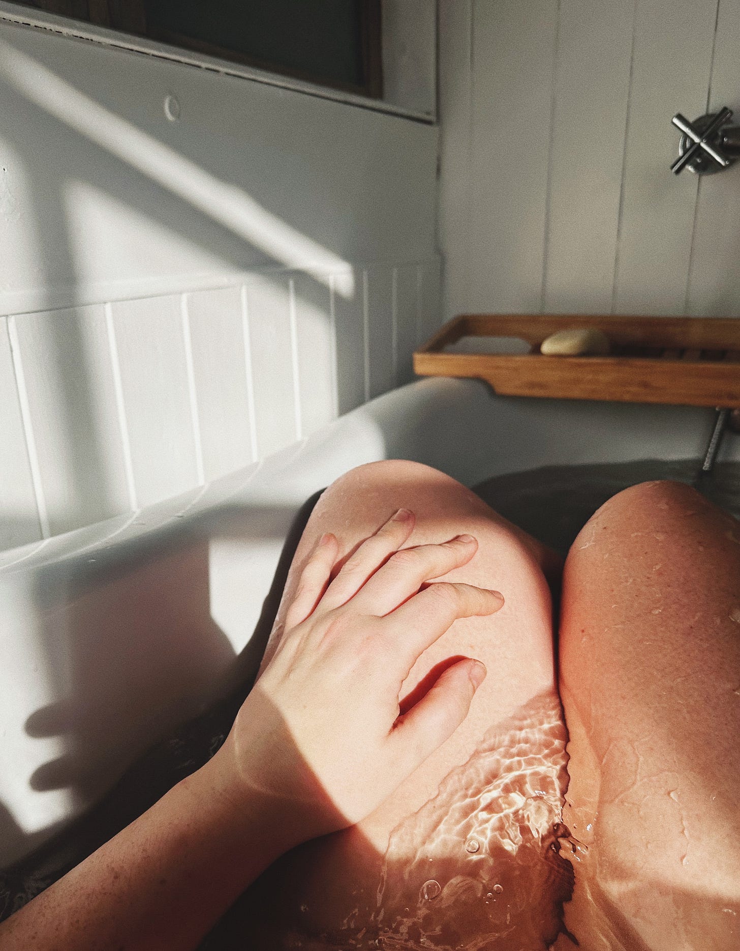 legs in a bathtub, with sunlight
