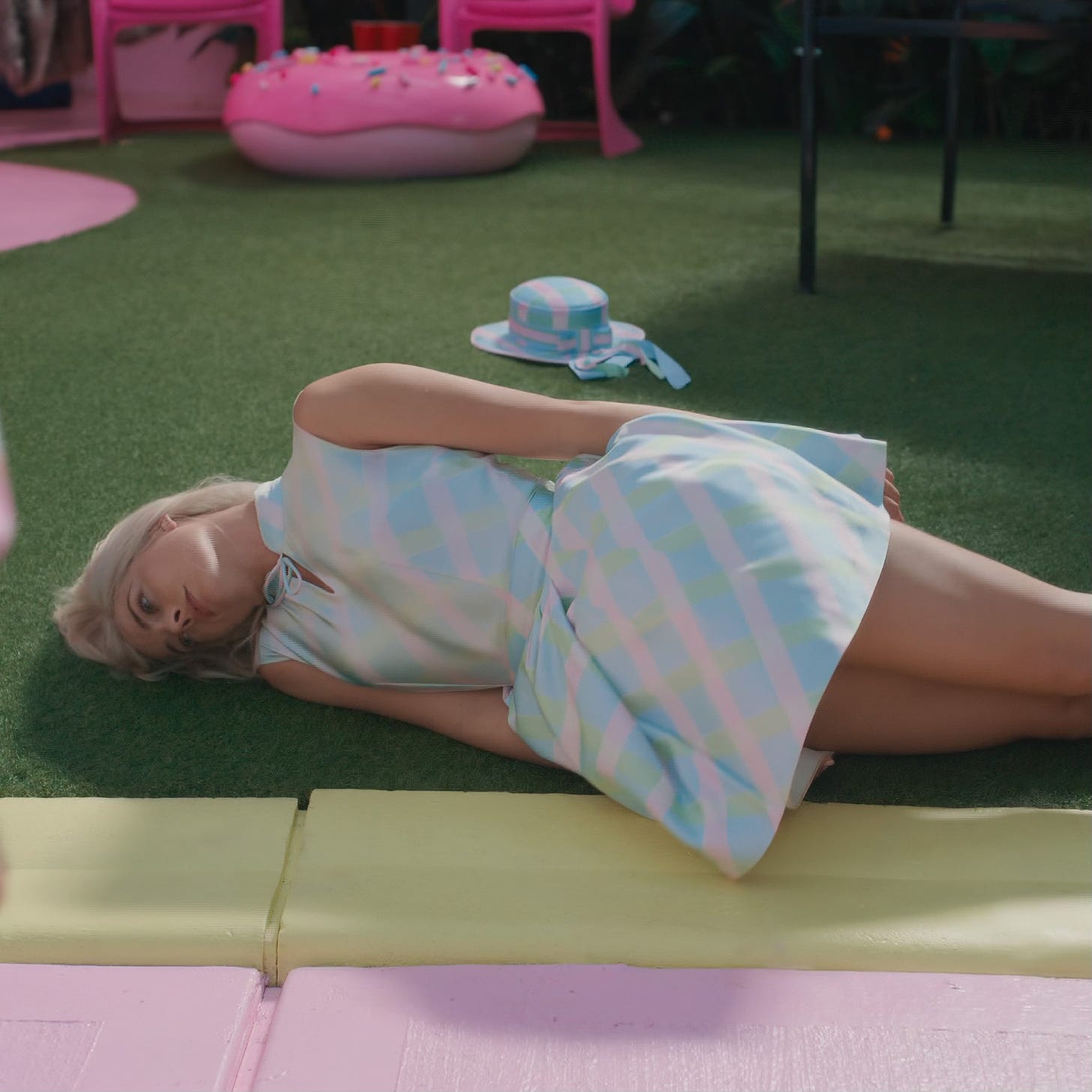 Margot Robbie as Barbie lying on the ground in Barbie land
