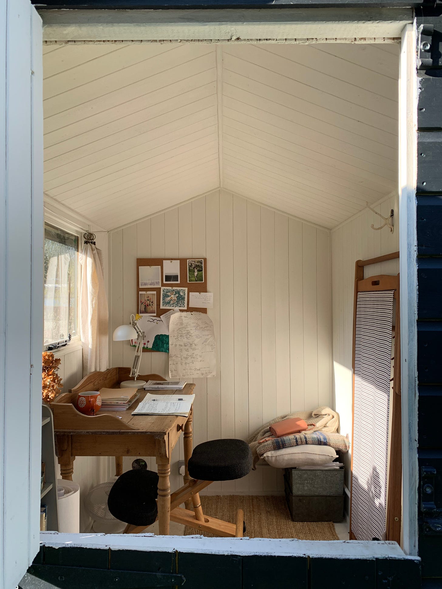 the interior of a writing shed with white walls and small wooden desk