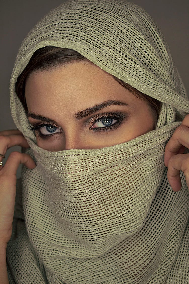Woman revealing her eyes with a cloth covering half her face.