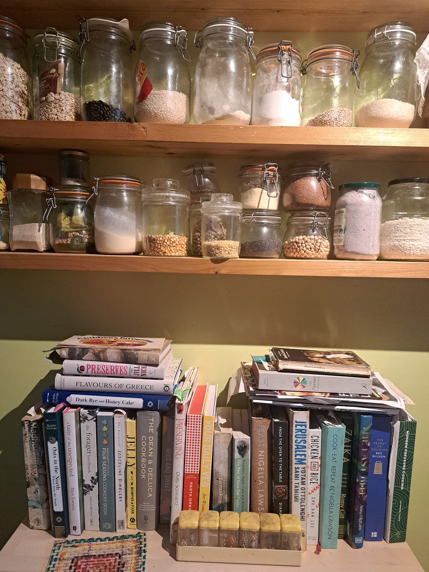 Storage jars and books on wooden shelves.