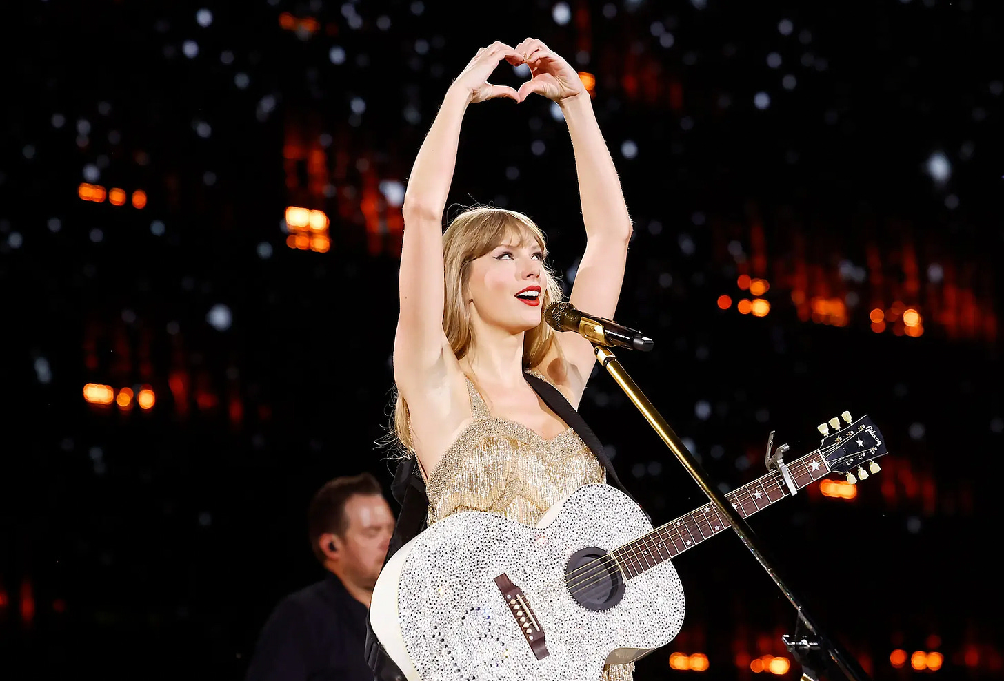Taylor Swift holding up a hand heart during the Fearless set at her Eras Tour.