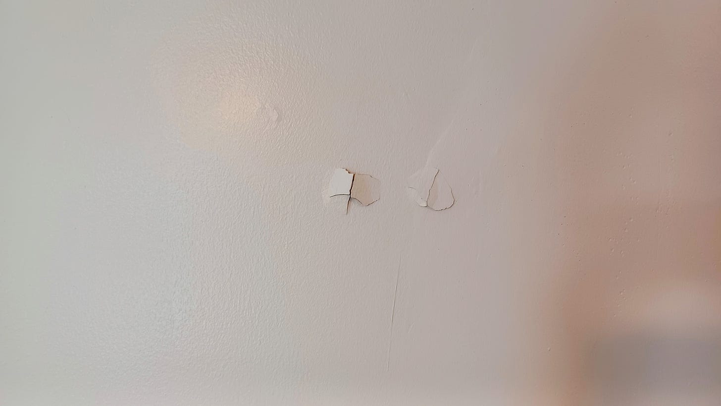 A wall with damage from long nails used to hang pictures.