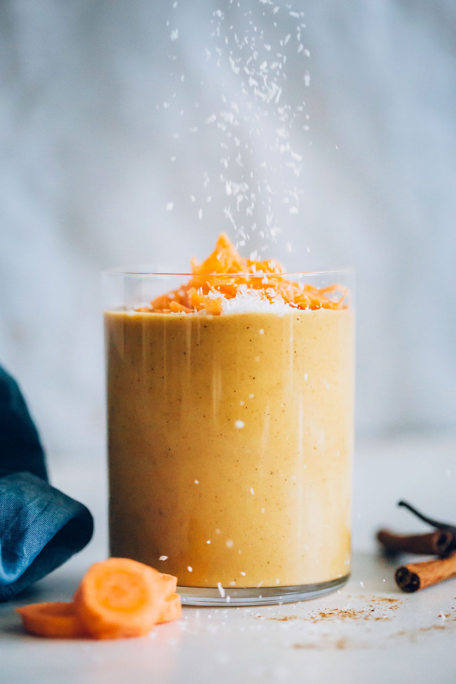 Sprinkling shredded coconut onto a Carrot Cake Smoothie