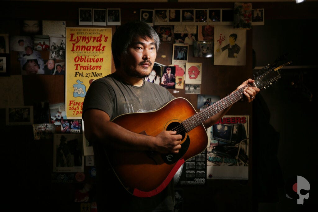 A picture of Mike Park holding an acoustic guitar.