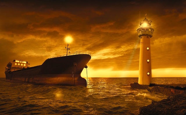 A ship and lighthouse under a red-ish sky.