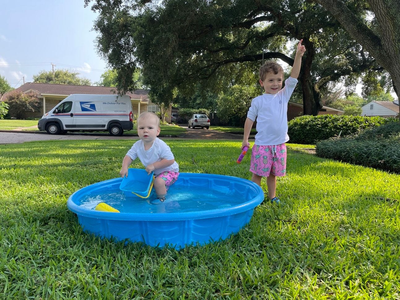 two youn boys playin in a plastic pool in the front yard two youn boys playin in a plastic pool in the front yard