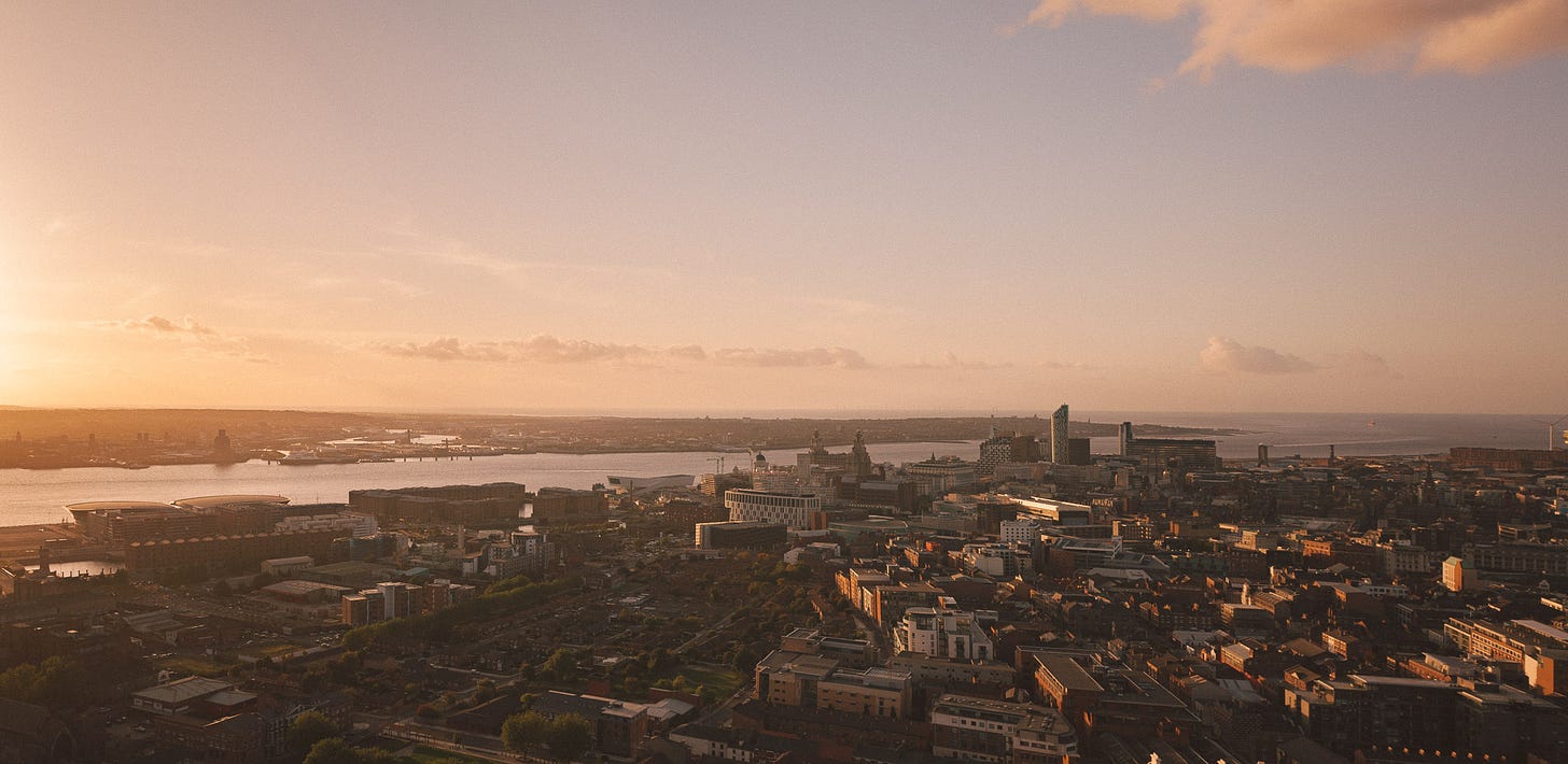 From the top of the Anglican Cathedral in Liverpool, the sun sets over the city. The view reaches out across the River Mersey across Wirral and out to the Liverpool Bay where there are wind turbines.