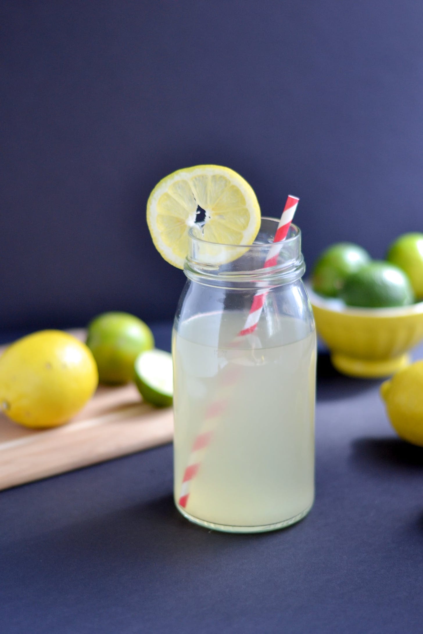 glass of homemade electrolyte drink with lemons and limes around it