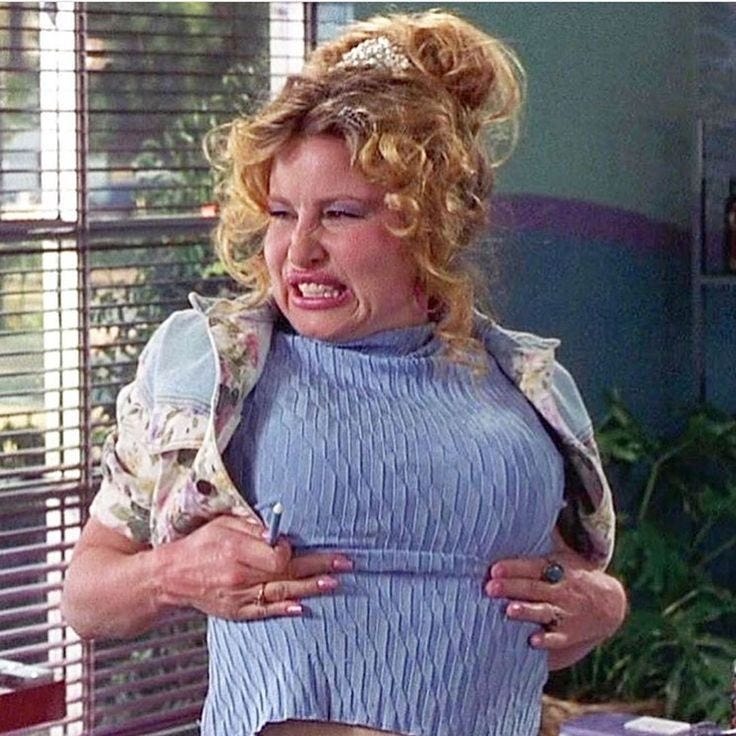 This may contain: a woman with blonde hair wearing a blue top and skirt in front of a window