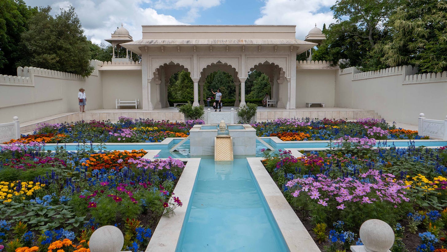 A view past a riot of colourful flowers and formal water features to a Taj Mahal-style arch