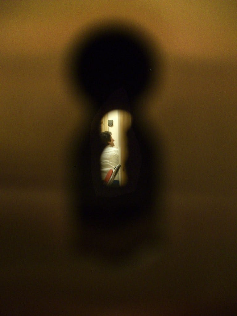 Mujo peers through the keyhole of a hotel room