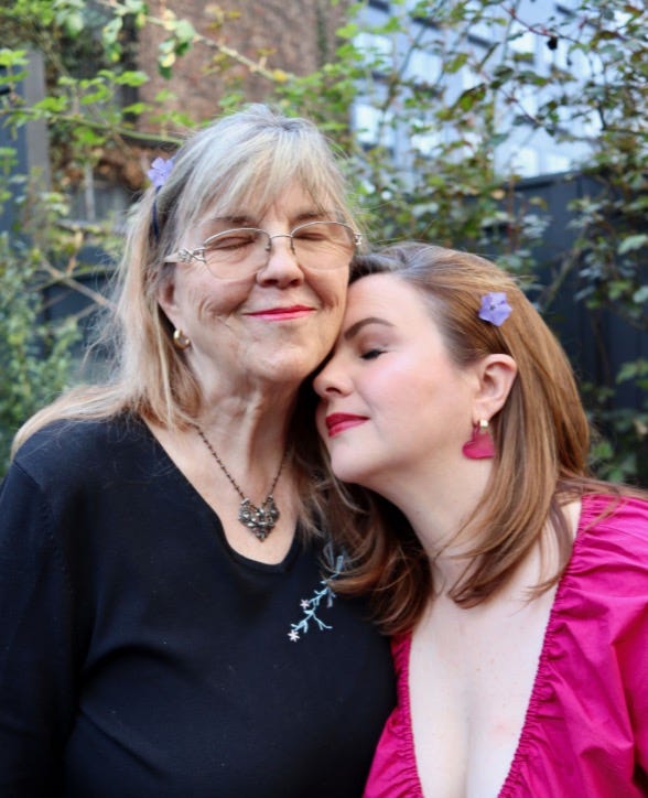 Amber and her mom, Bonnie, stand outside together. They both have their eyes closed and slight smiles on their faces. Amber is turned so that her forehead lovingly rests on her mother's cheek.