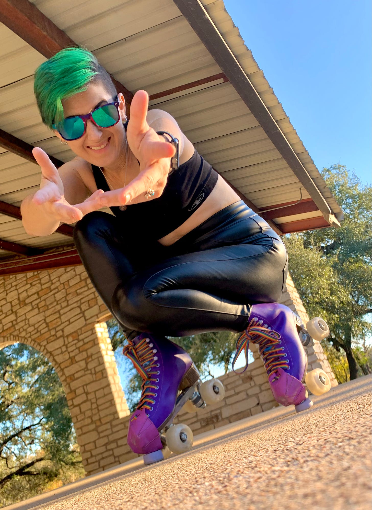 Lyric Posing in black leather pants, on the toe stops of their purple roller skates, pointing both hands out at the camera