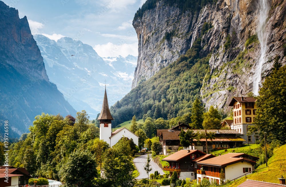 Great view of alpine village glowing by sunlight. Location Swiss alps, Lauterbrunnen valley, Staubbach waterfall, Europe.