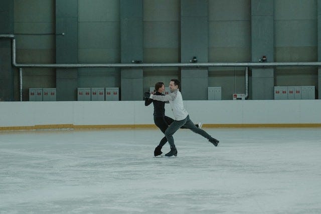 two figure skaters skating in an embrace with their legs extended, aligned