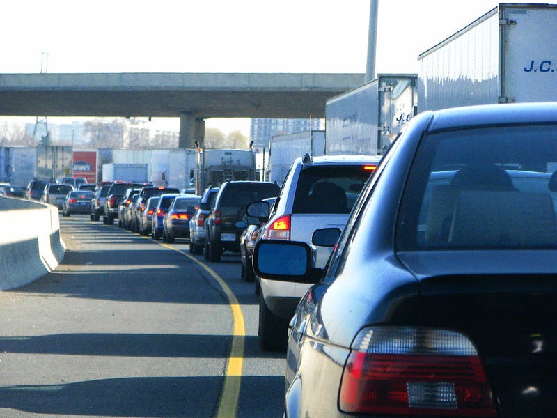 Bumper-to-bumper cars on a highway with brake lights visible.