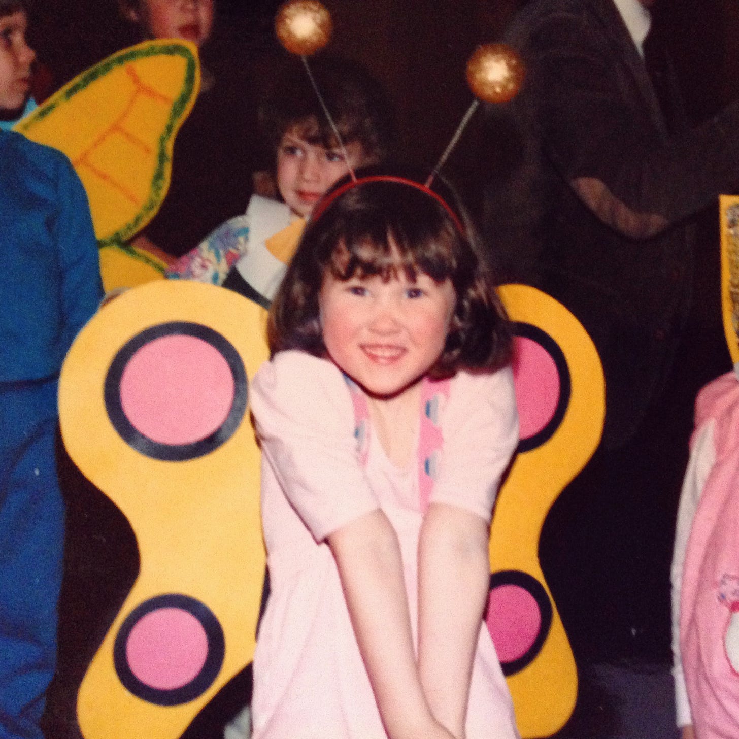 Kathryn as a child, wearing a pink leotard, pink and yellow butterfly wings, and sparkly gold antennae.