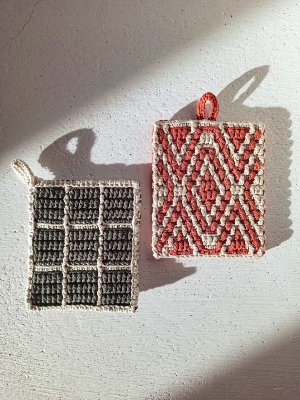 Overlay mosaic crochet potholders in white and rust orange, and white and olive green.