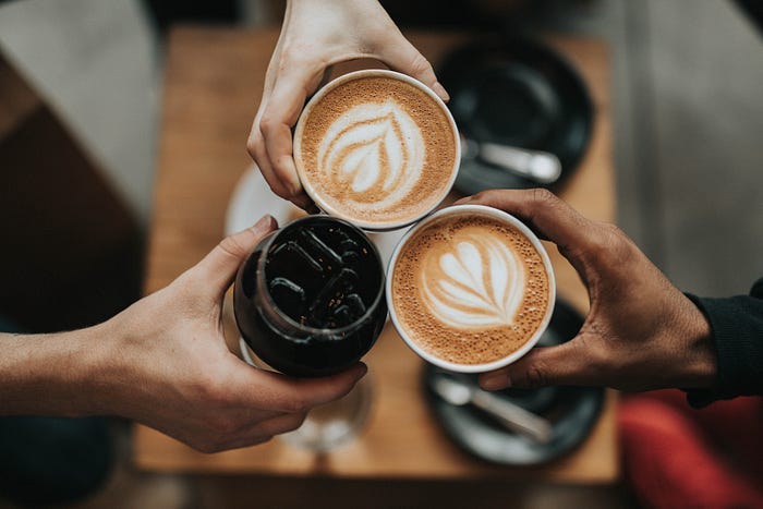 Three people clink their drinks together in a show of solidarity. Three people clink their drinks together in a show of solidarity.