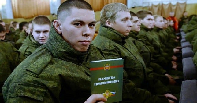 A Russian soldier sits with other new conscripts 