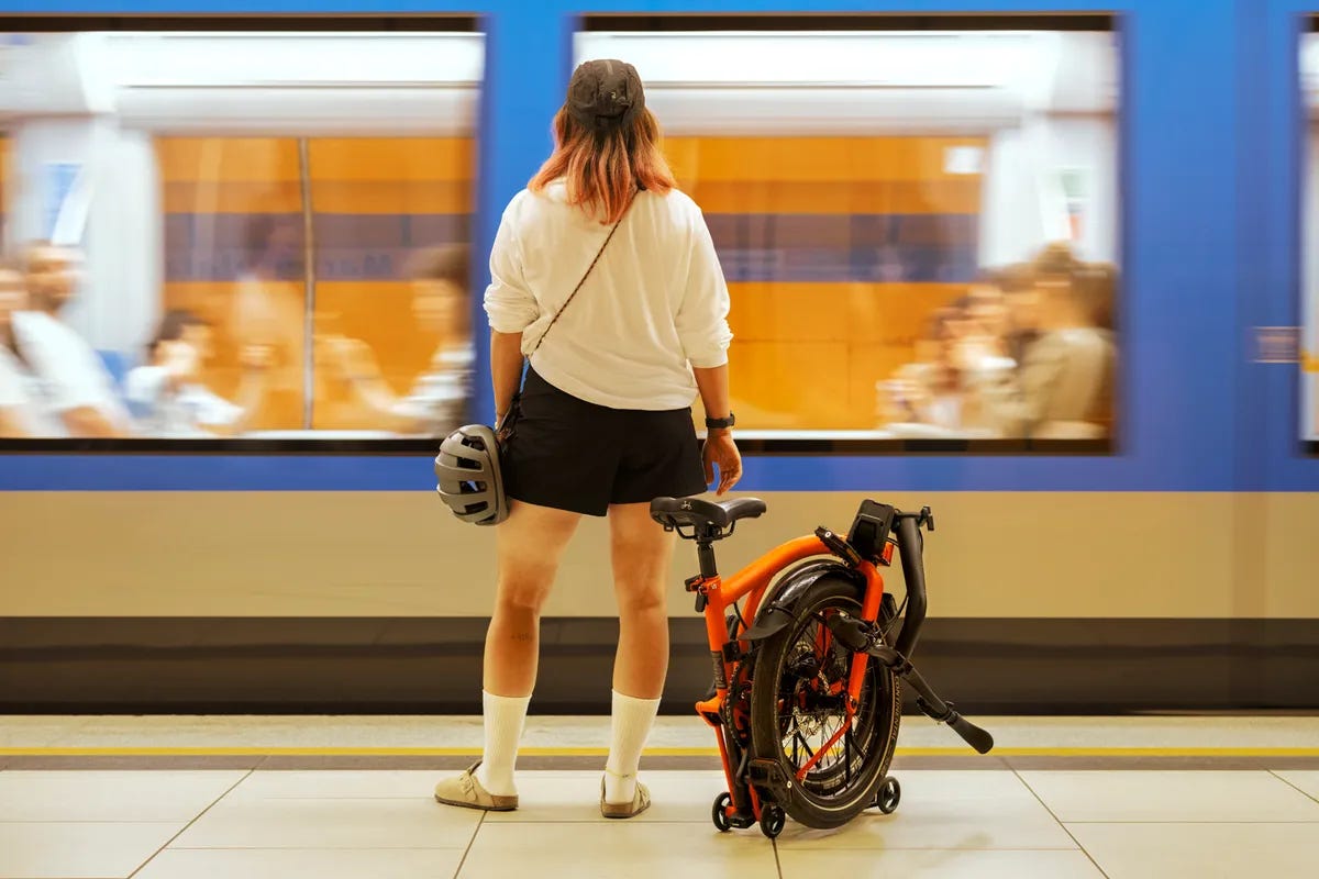 Woman standing with Brompton G Line on platform as train goes by.