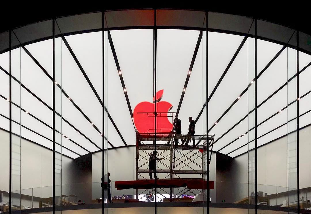 Employees on scaffolding install a RED Apple logo at Apple Xinjiekou.