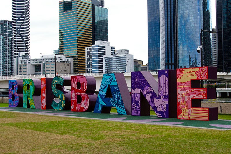 A colourful sign spelling out ‘Brisbane’ against the backdrop of the city skyscrapers.