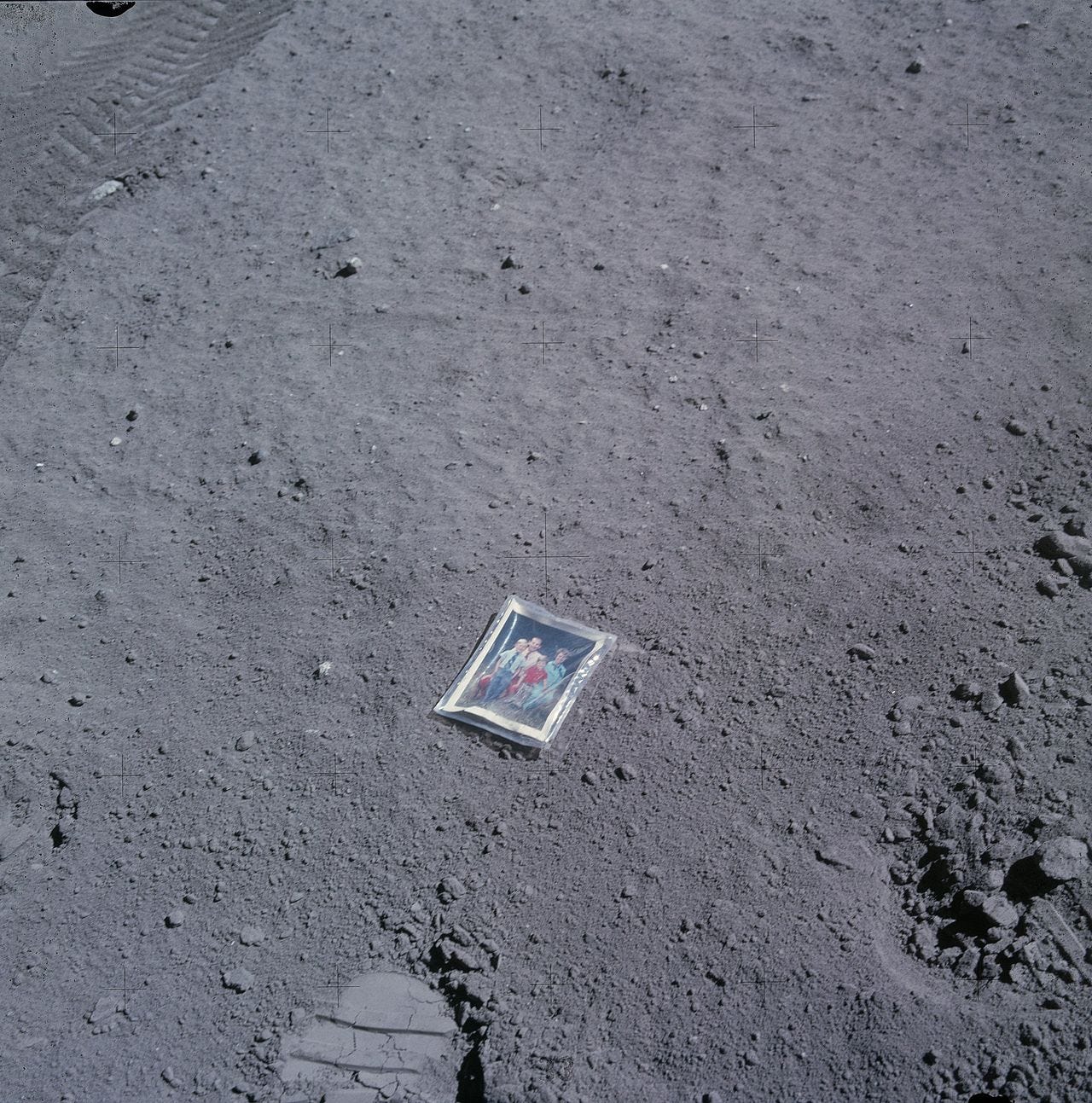 A small family photo in plastic on the gray lunar surface.