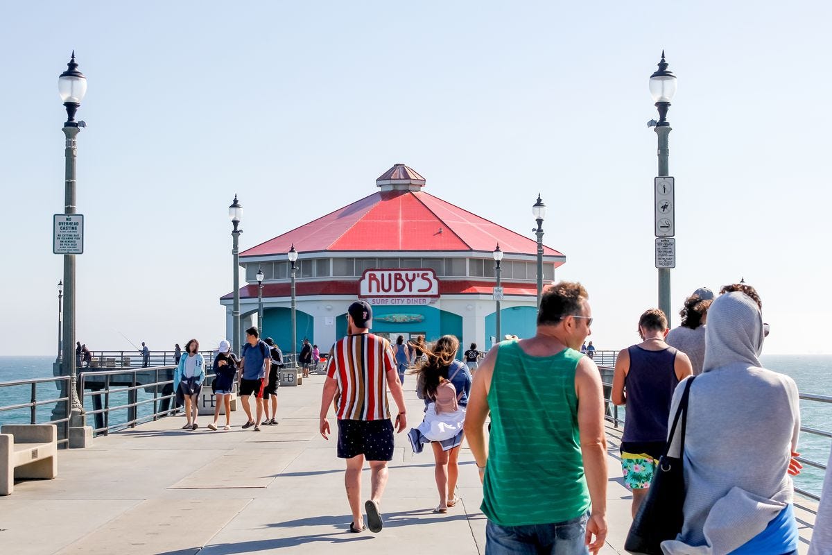 People walk towards the end of the pier where Ruby’s awaits on a sunny day. 