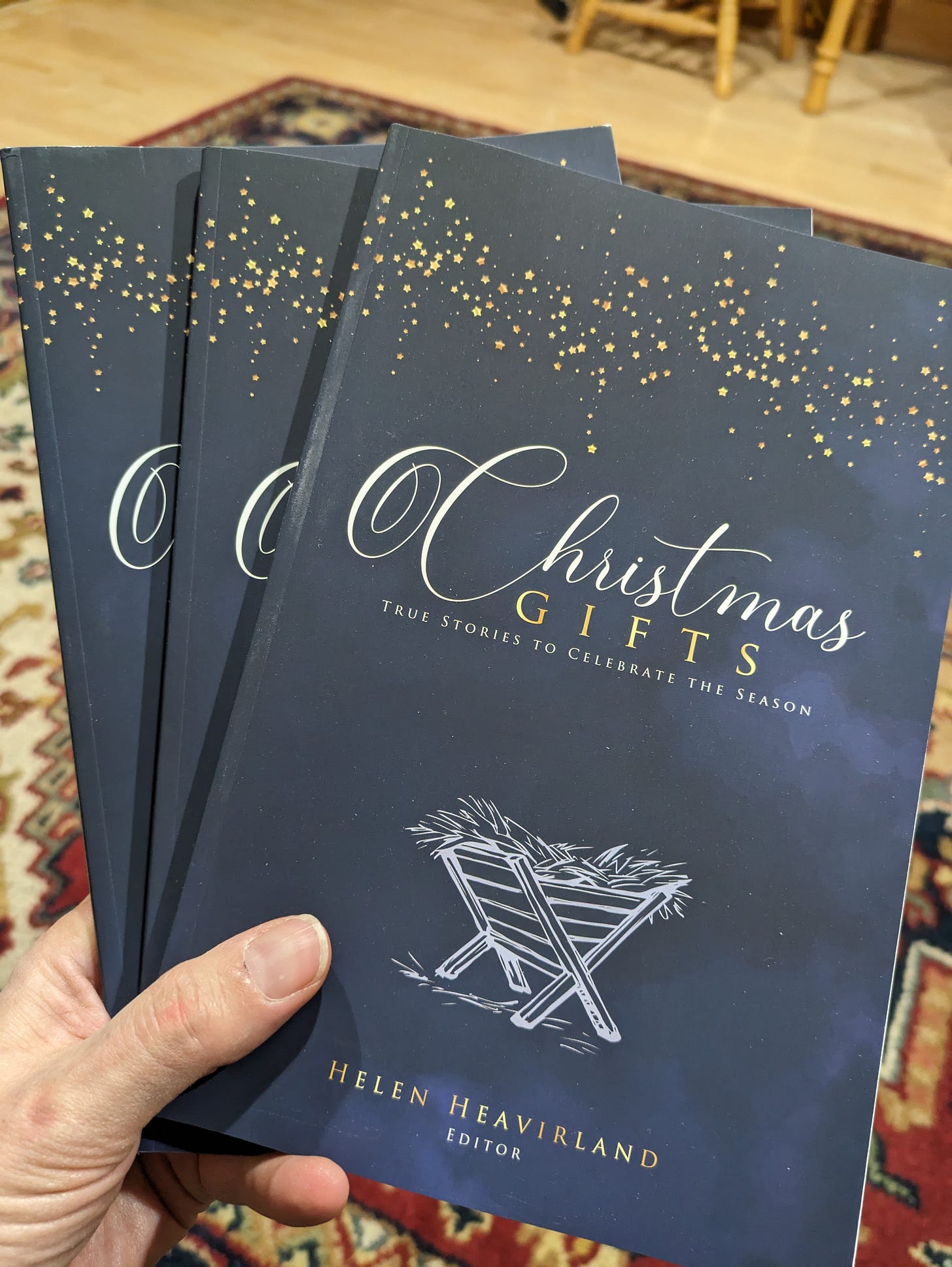 Holding a stack of books entitled Christmas Gifts: True stories to celebrate the season