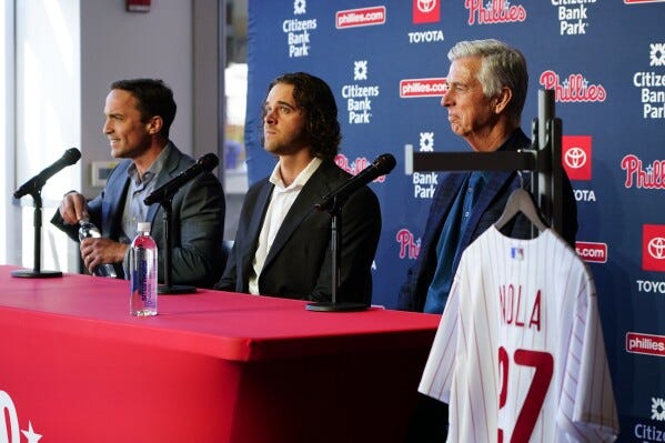 Philadelphia Phillies baseball team pitcher Aaron Nola, center, takes questions from the media after signing a seven-year contract, with President of Baseball Operations David Dombrowski, right, and Vice President and General Manager Sam Fuld, left, Monday, Nov. 20, 2023, in Philadelphia. (AP Photo/Chris Szagola)