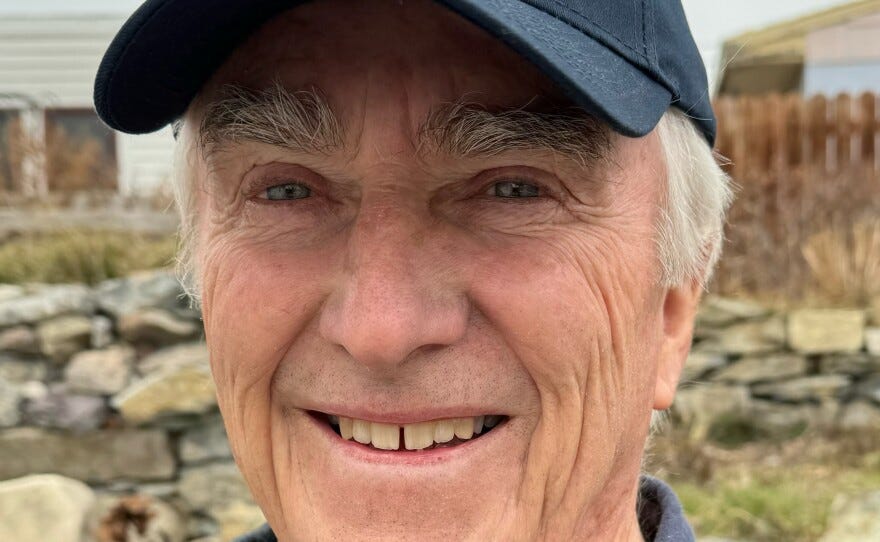 close up photo of man smiling in blue hat in yard