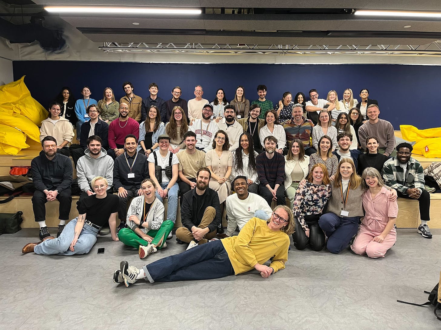 A photo of ~50 smiling people sat on bleachers