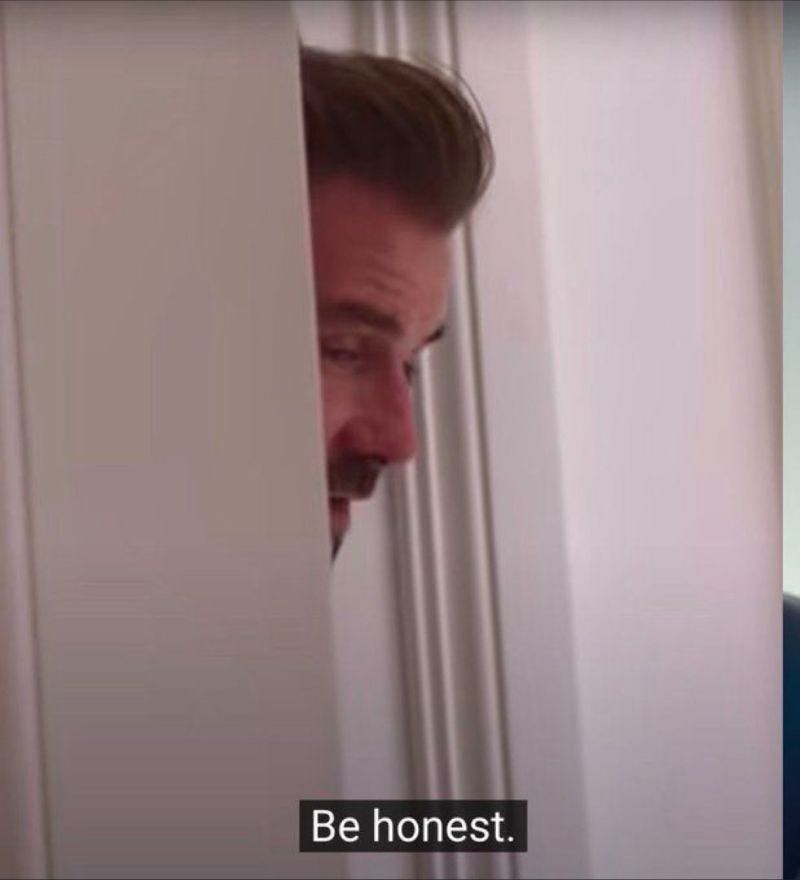 Still of the Beckham documentary on Netflix. It’s David Beckham with his head in the doorway, imploring his wife Victoria to “Be honest” about a question she’s answering. 