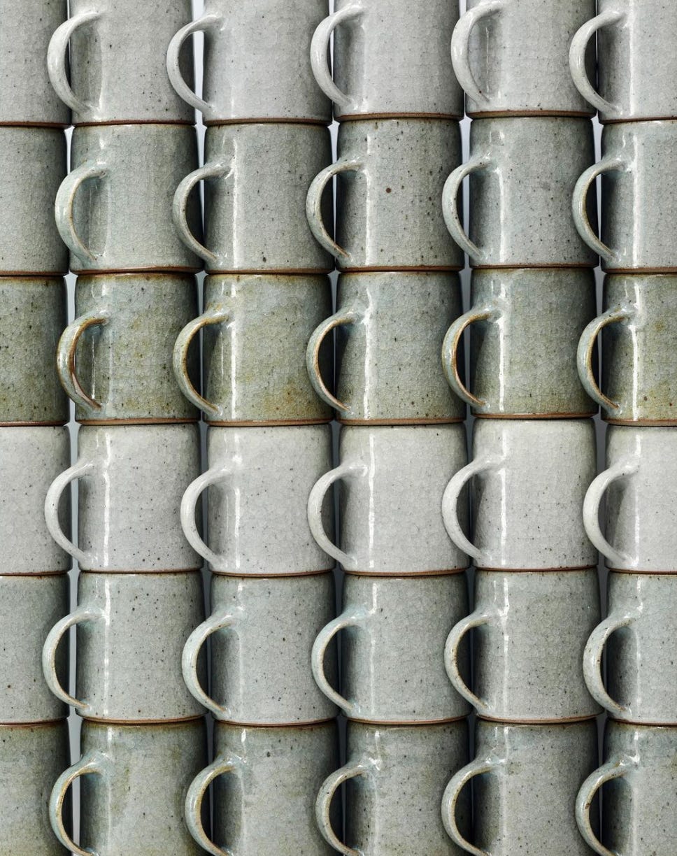 various shades of green ceramic mugs all stacked on top of each other