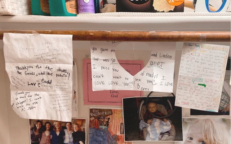 Some thank-you notes and pictures taped up on a laundry room wall.