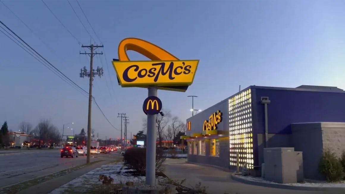 imagem da fachada do novo restaurante do McDonald's, que tem uma placa escrito "CosMc's" na frente, em amarelo com uma letra levemente cursiva, de ar retrô. o restaurante é de um azul próximo do lavanda, e tem luzes amarelas na frente.