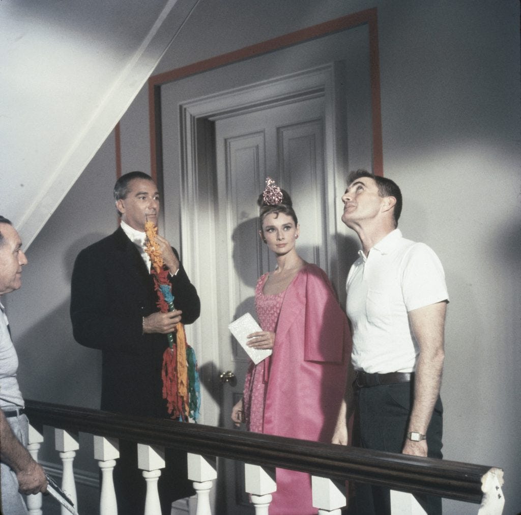 An image from Breakfast at Tiffany's of Holly standing outside her apartment with two different gentlemen