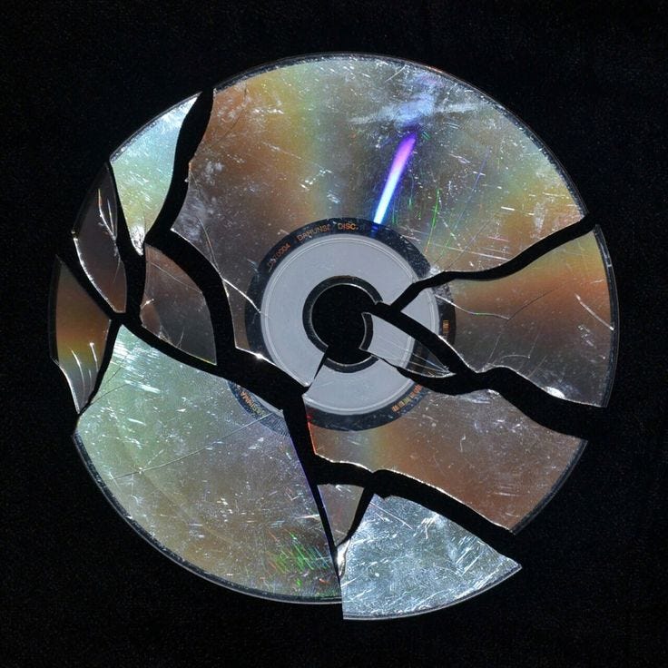This may contain: a broken cd that is sitting in the dark