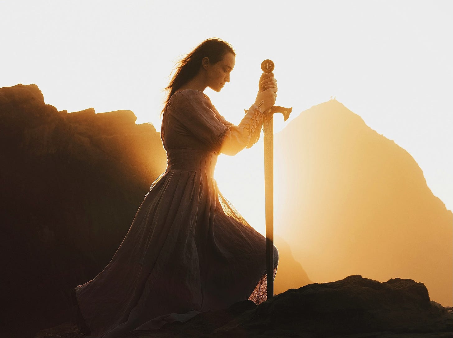 Woman with sword kneeling in sunset